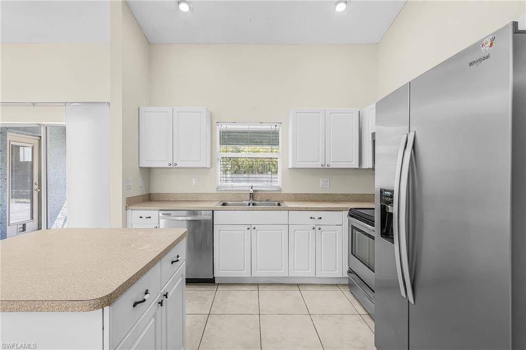 Kitchen featuring stainless steel appliances, white cabinetry, light-toned countertops, and tile flooring