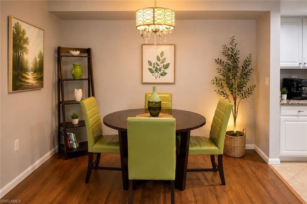 Intimate dining area featuring a round wood-finish table, chartreuse upholstered chairs, and wood flooring throughout