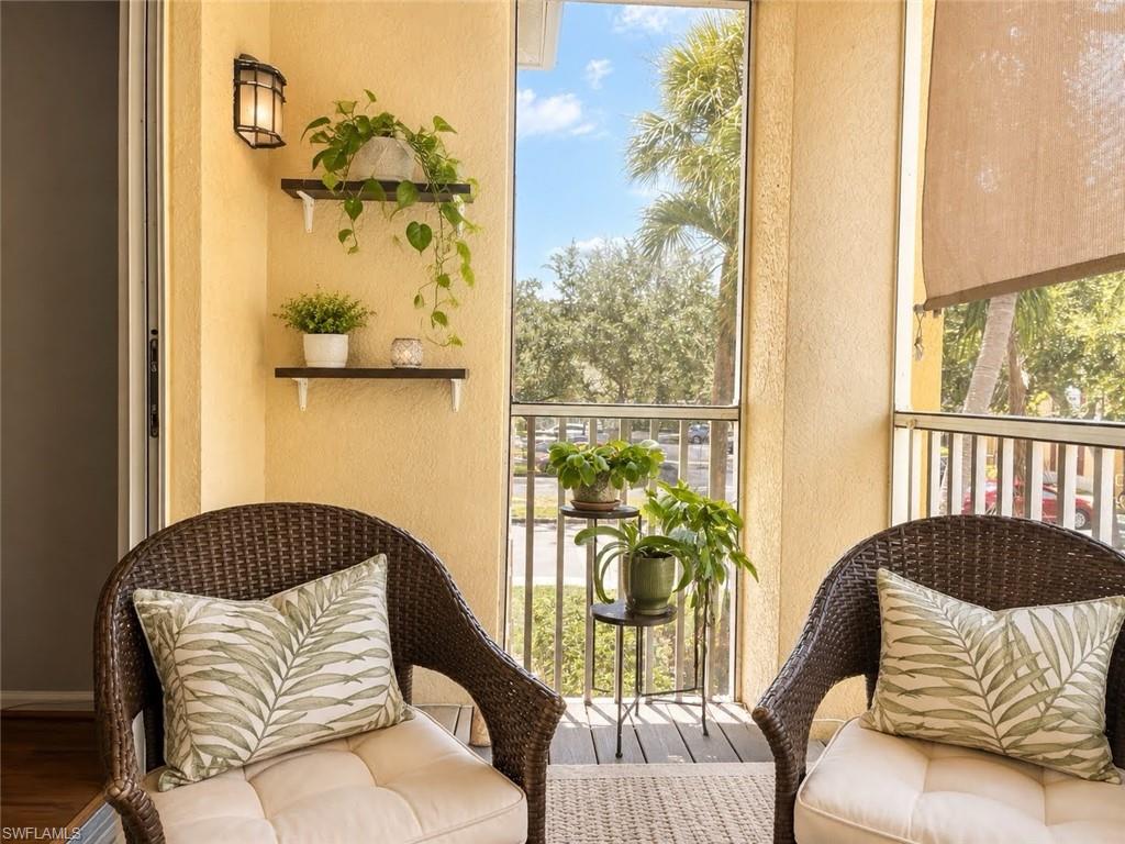 Screened balcony with textured walls, equipped with a wall-mounted light fixture, and featuring a roll-down shade