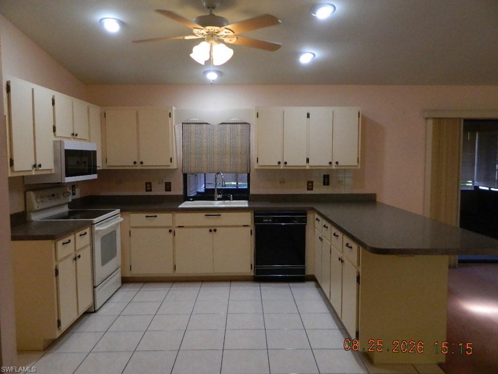 Kitchen featuring white cabinetry, dark countertops, white tile flooring, recessed lighting, and a ceiling fan