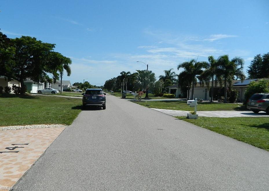 Wide, tree-lined street with mature palms and established landscaping