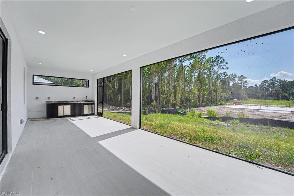 Covered patio with recessed lighting, a built-in outdoor kitchen with a sink, and a panoramic screened enclosure