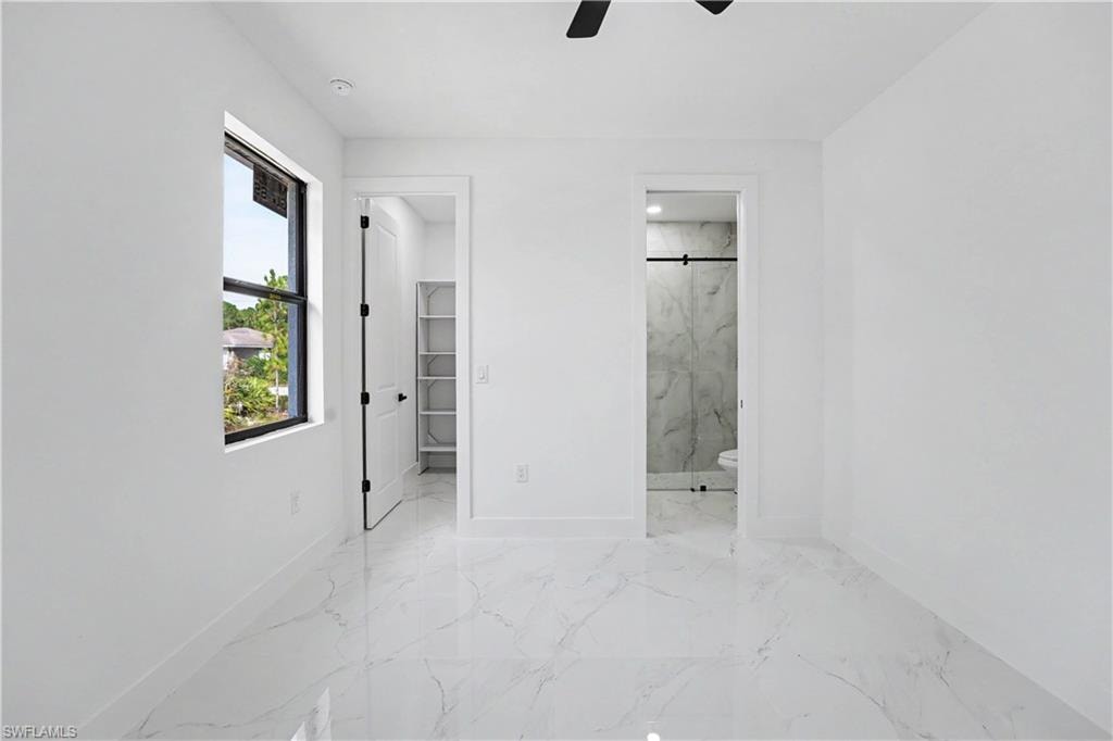 White marble-look flooring, built-in shelving, and a modern ceiling fan