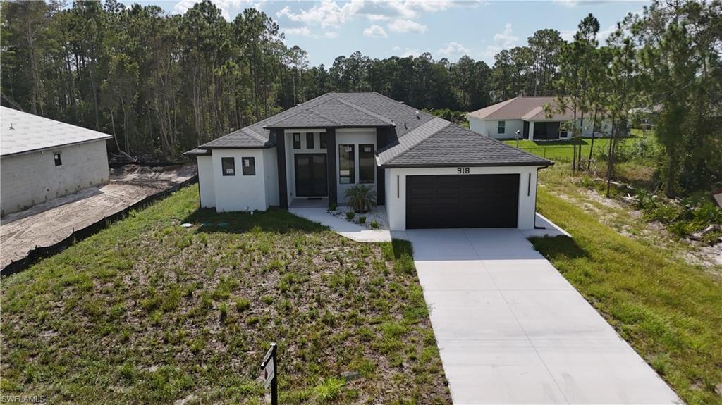 Modern residence featuring a striking two-tone exterior with crisp white and charcoal finishes, complemented by a wide concrete driveway and attached two-car garage