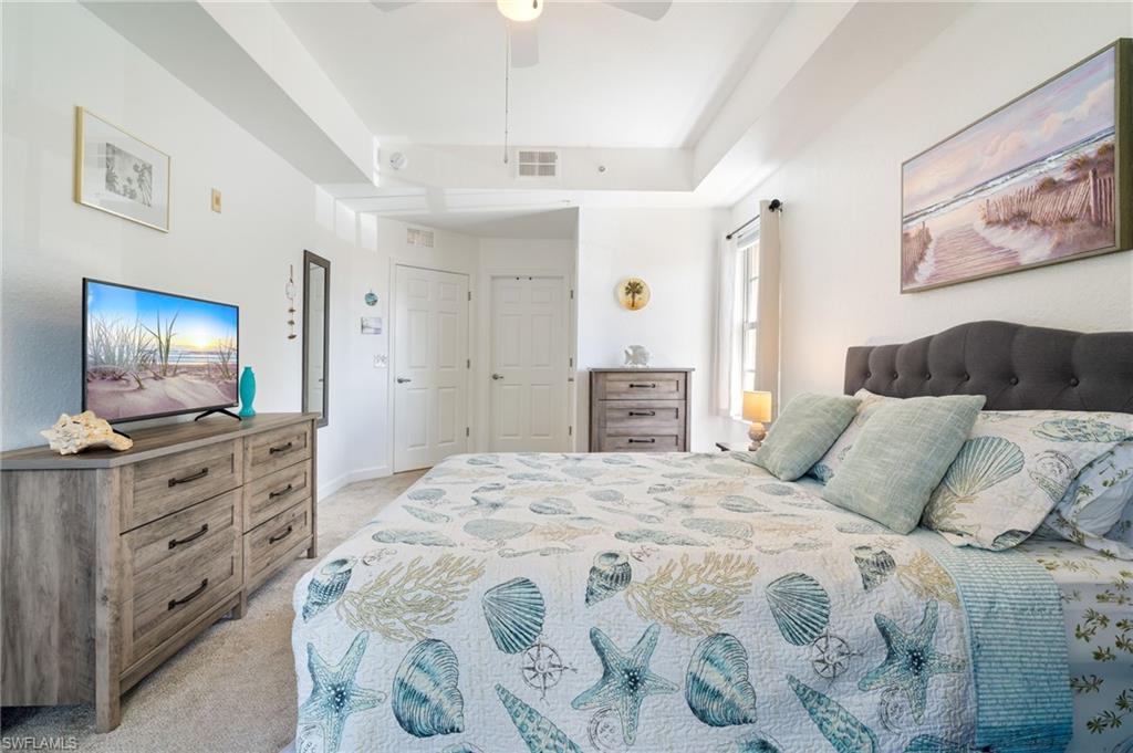 Recessed ceiling with an overhead fan, carpeted flooring, and a large window with curtain rods