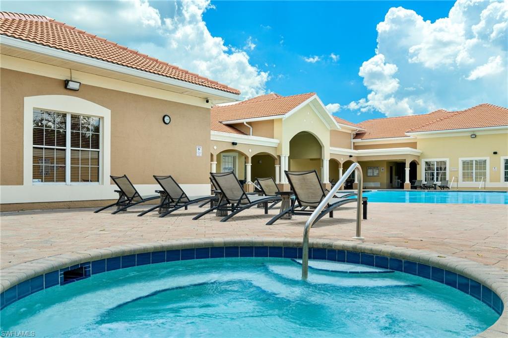 Resort-style backyard oasis featuring a sparkling saltwater pool with integrated spa, travertine decking, lounge seating areas, and a spacious covered lanai with arched architectural detailing