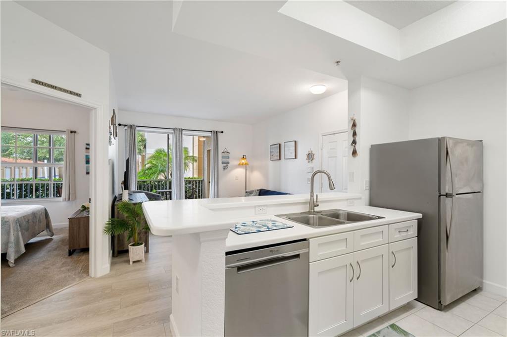Kitchen featuring a dual basin sink, stainless steel appliances, white cabinetry, and a breakfast bar