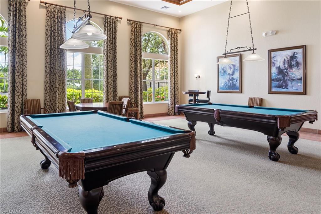 Spacious recreation room featuring two billiard tables, arched windows, and recessed lighting