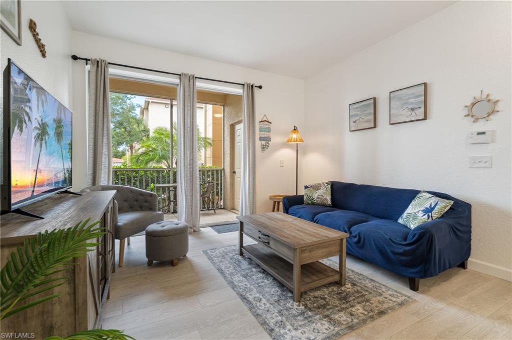 Living area with light-toned flooring, a wood-finish media console, and direct access to an outdoor balcony