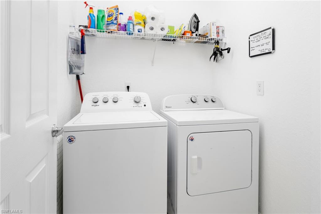 Dedicated laundry room featuring side-by-side washer and dryer with top-load and front-load configurations, white finish cabinetry, wall-mounted shelving with ample storage for household supplies, and neutral tile flooring