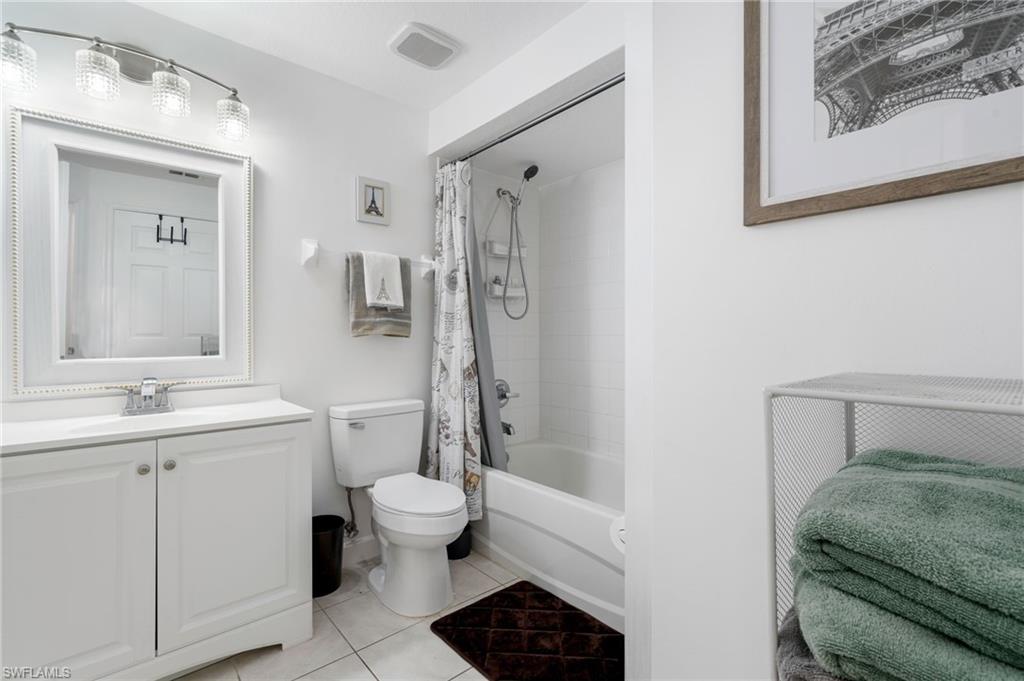 White vanity with cabinet storage, framed mirror, and a three-light fixture