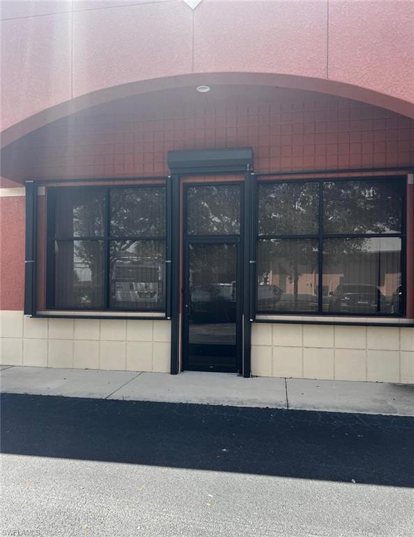 Red brick exterior with an arched entryway, recessed lighting, and a glass paneled door