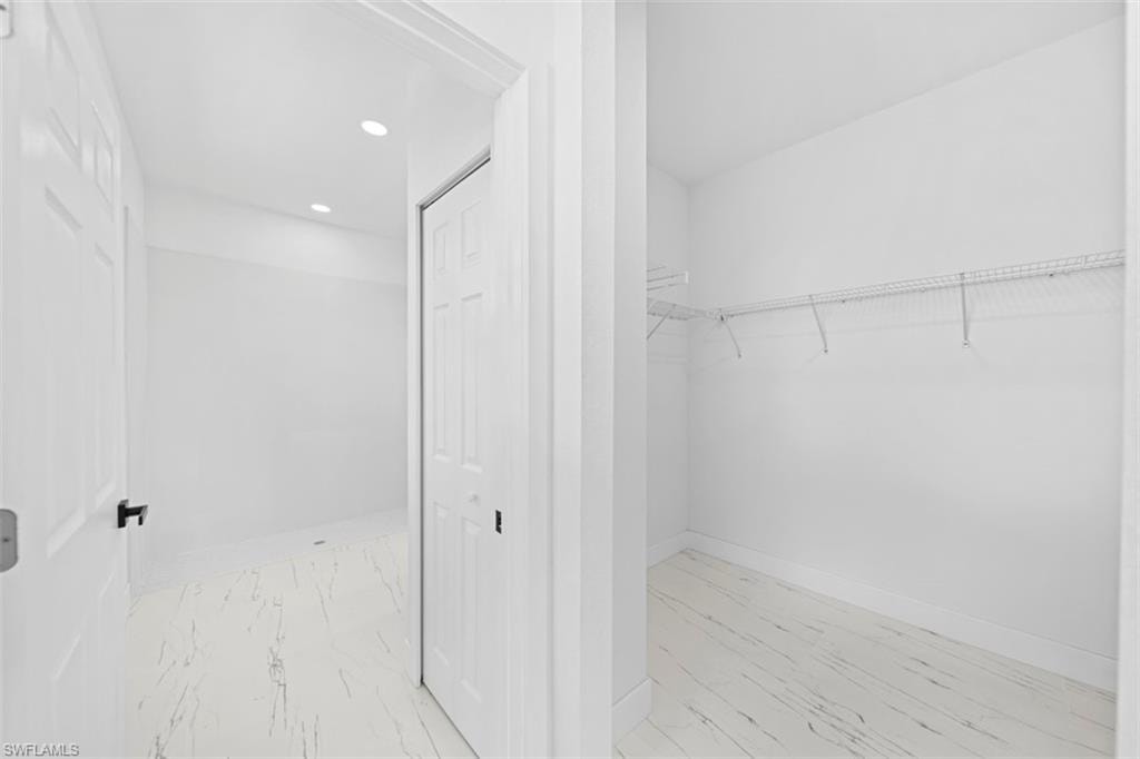 White tile flooring with subtle veining, recessed ceiling lighting, and a closet with wire shelving