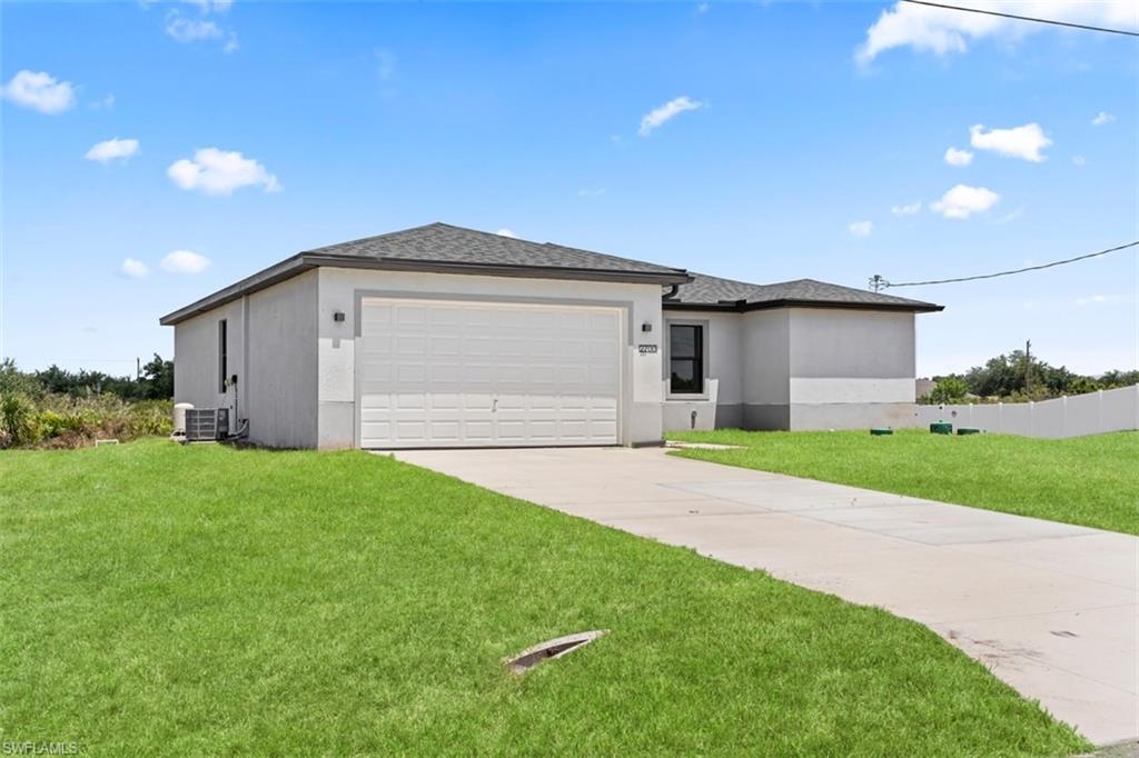 Attached two-car garage, concrete driveway, stucco exterior, shingle roof, and green lawn