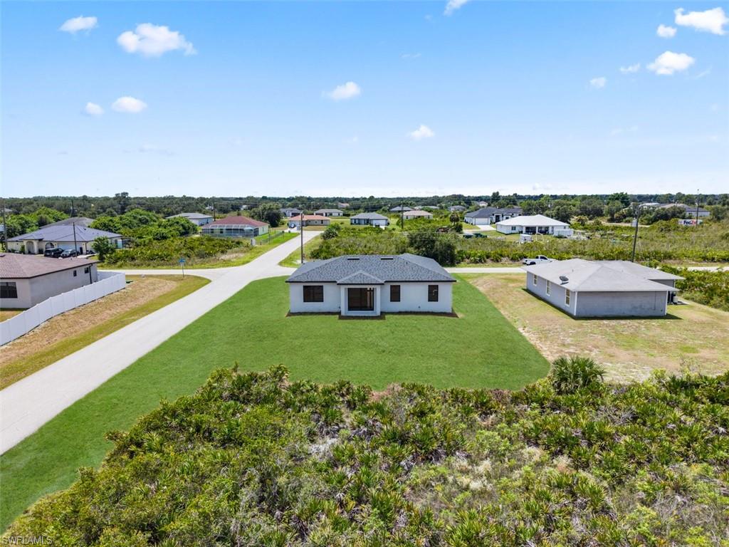 Newly constructed residence with a dark shingle roof and a light-toned exterior, situated on a verdant lawn