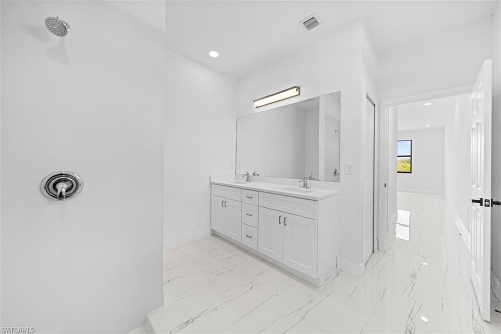 Spacious bathroom with a walk-in shower, dual vanity, and large framed mirror
