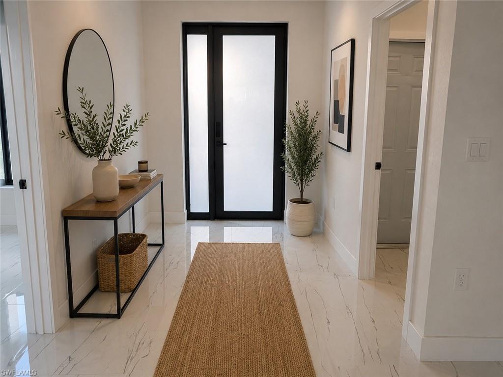 Bright entryway with light-filled glass and black-frame doors, light wood-finish flooring, and white painted walls
