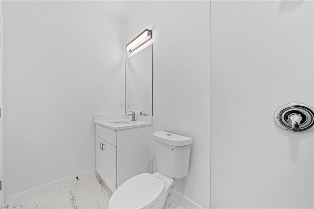 White vanity with a rectangular sink, wall-mounted mirror, and contemporary light fixture