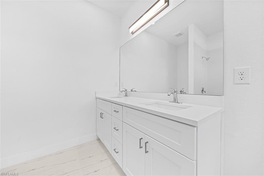 Dual-sink vanity with white cabinetry, integrated sinks, and polished chrome faucets