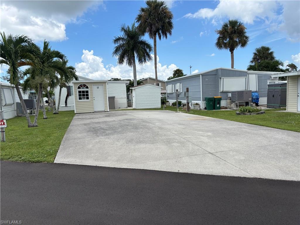 Paved driveway with adjacent manicured lawn and mature palm trees