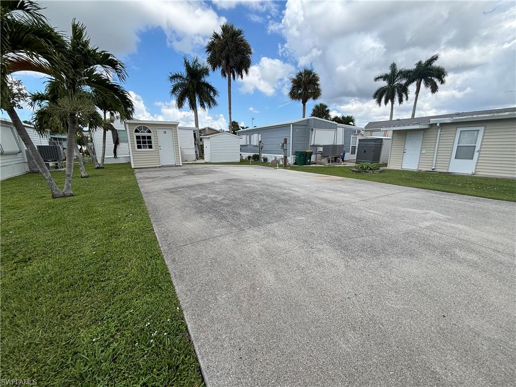 Expansive concrete driveway with surrounding green lawn and mature palm trees