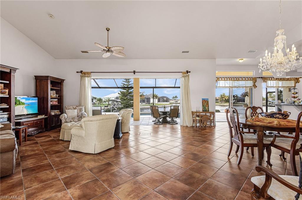 Living area featuring a chandelier, high vaulted ceiling, dark tile patterned floors, and a ceiling fan