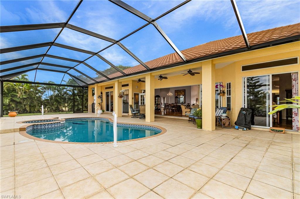 View of pool with glass enclosure, a sunroom, a pool with connected hot tub, and a patio