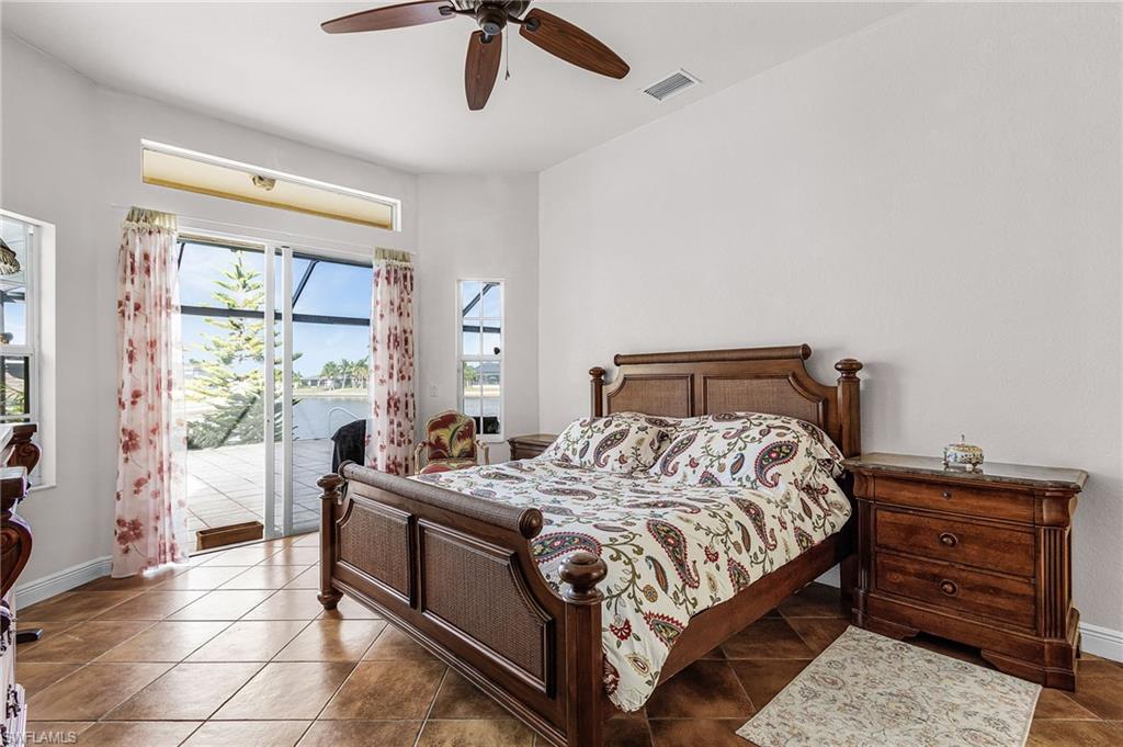 Bedroom featuring access to exterior, a ceiling fan, a water view, and tile patterned flooring
