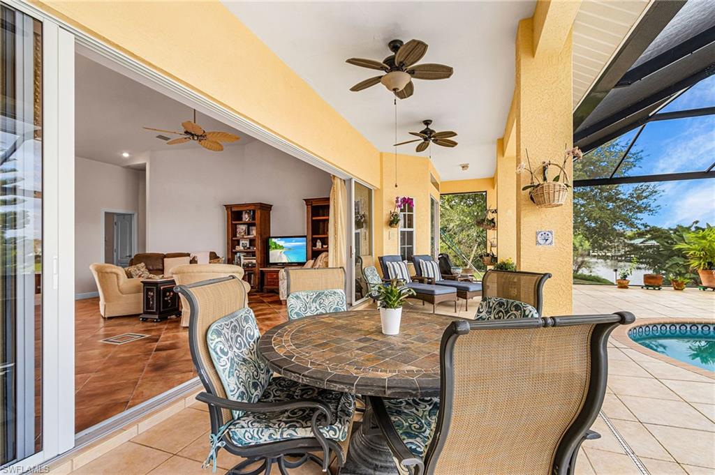 View of patio / terrace featuring a lanai, a sunroom, outdoor dining area, a ceiling fan, and an outdoor pool