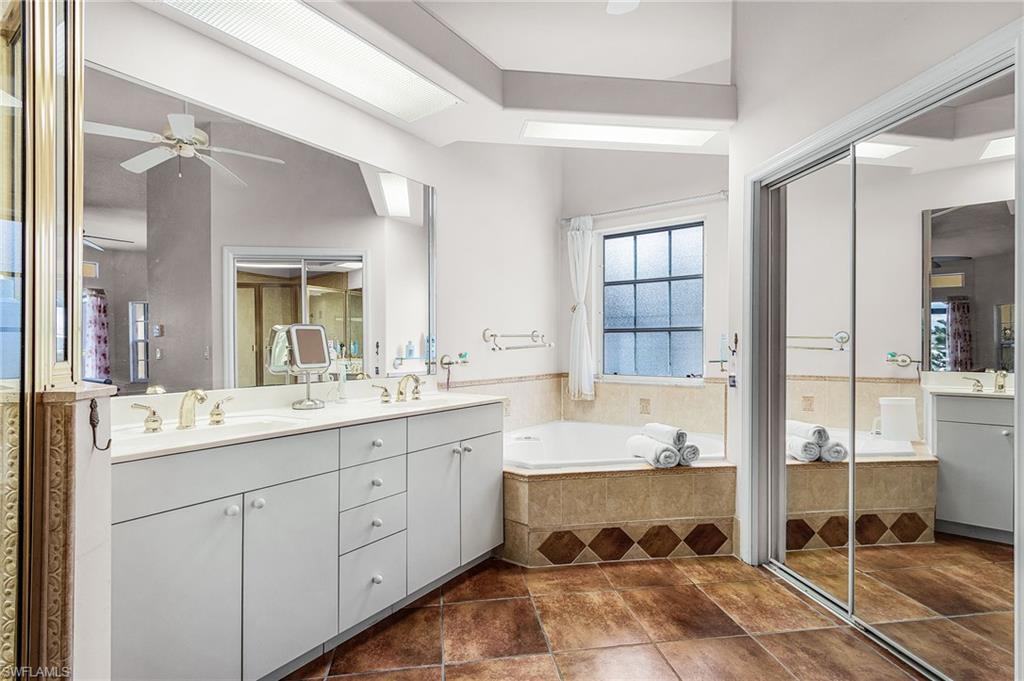 Full bath with double vanity, a bath, and ceiling fan