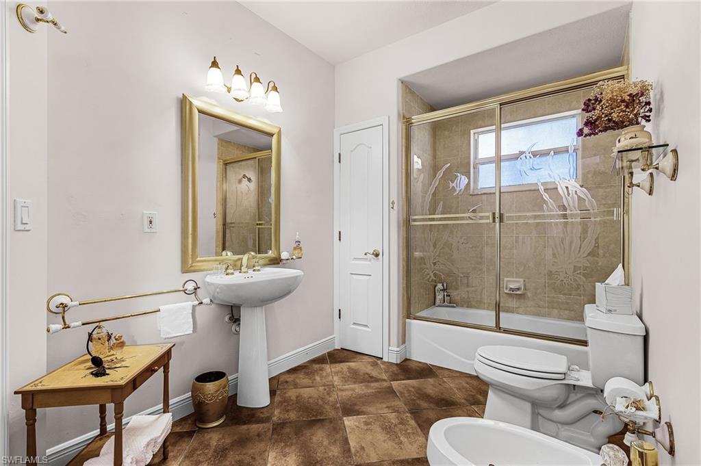 Bathroom with a bidet and bath / shower combo with glass door