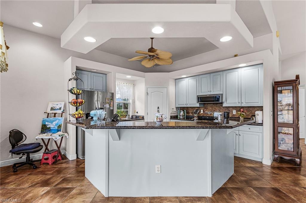 Kitchen featuring dark stone counters, a breakfast bar, recessed lighting, a kitchen island, and backsplash