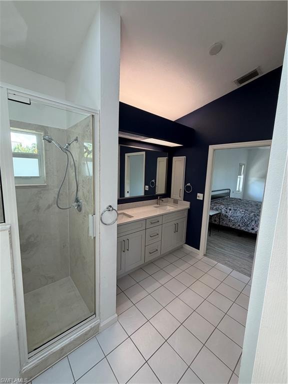 Primary bathroom featuring dual vanity with ample storage, ceramic tile flooring, framed mirrors, and glass-enclosed shower with tile surround and chrome fixtures