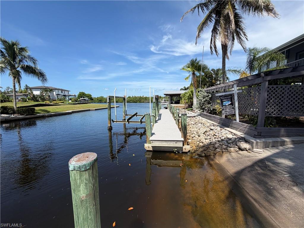 Private dock with boat lift, direct water access, and mature palm trees