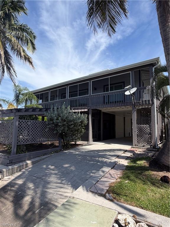 Elevated home featuring a modern architectural design with expansive covered upper-level deck and multiple windows