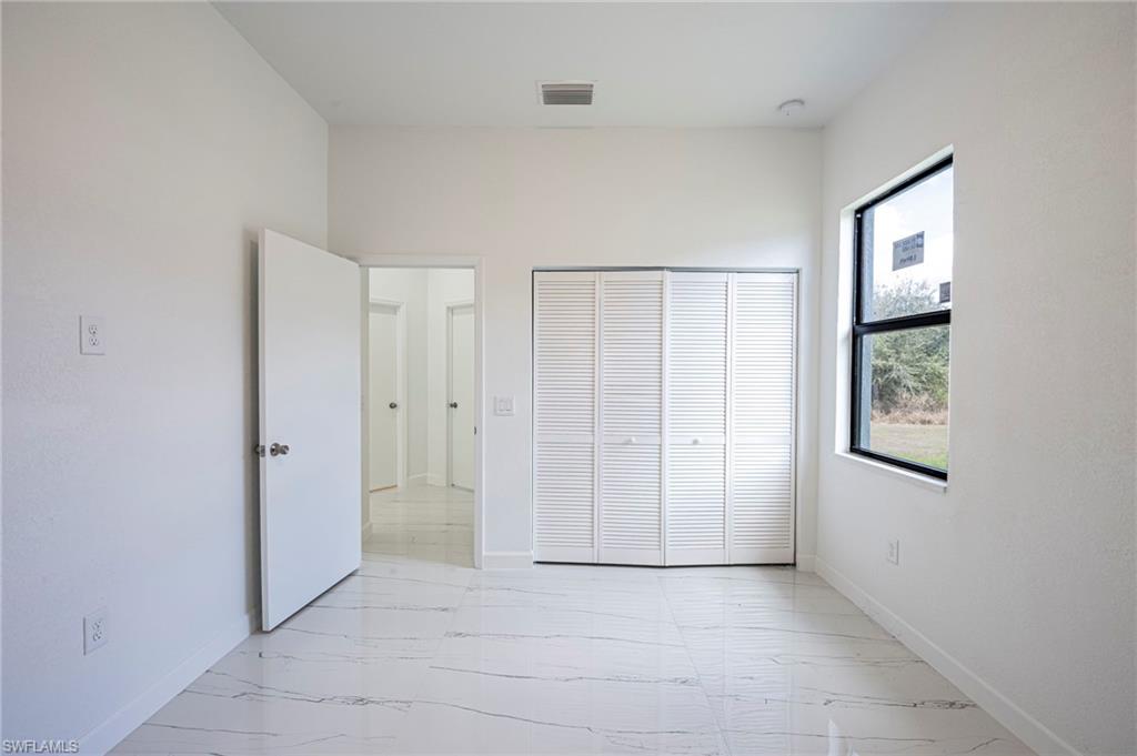 Unfurnished bedroom with light marble finish floors and a closet