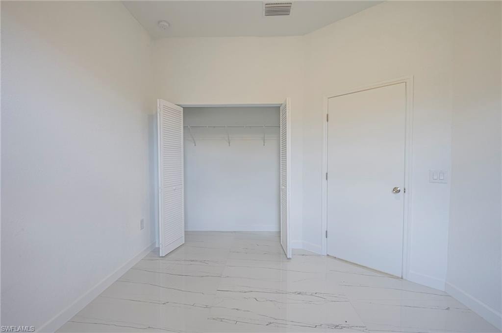 Unfurnished bedroom featuring light marble finish flooring and a closet
