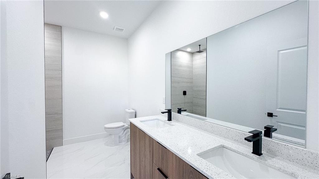 Contemporary bathroom featuring dual vanities with white quartz countertops, wood-finish cabinetry, and matte black fixtures