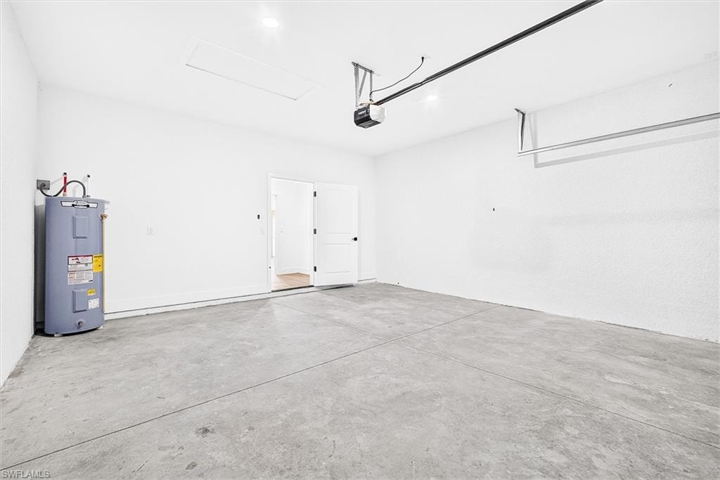 Spacious garage with polished concrete flooring, white drywall, overhead door, and integrated water heater
