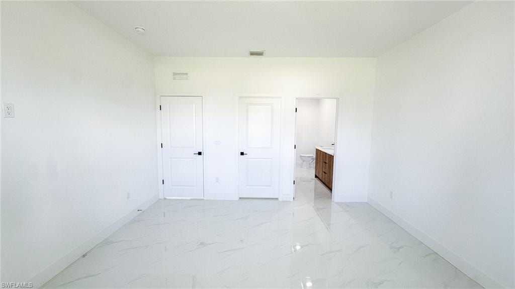 Spacious interior featuring pristine polished concrete flooring, bright white walls, and multiple white six-panel doors with black hardware