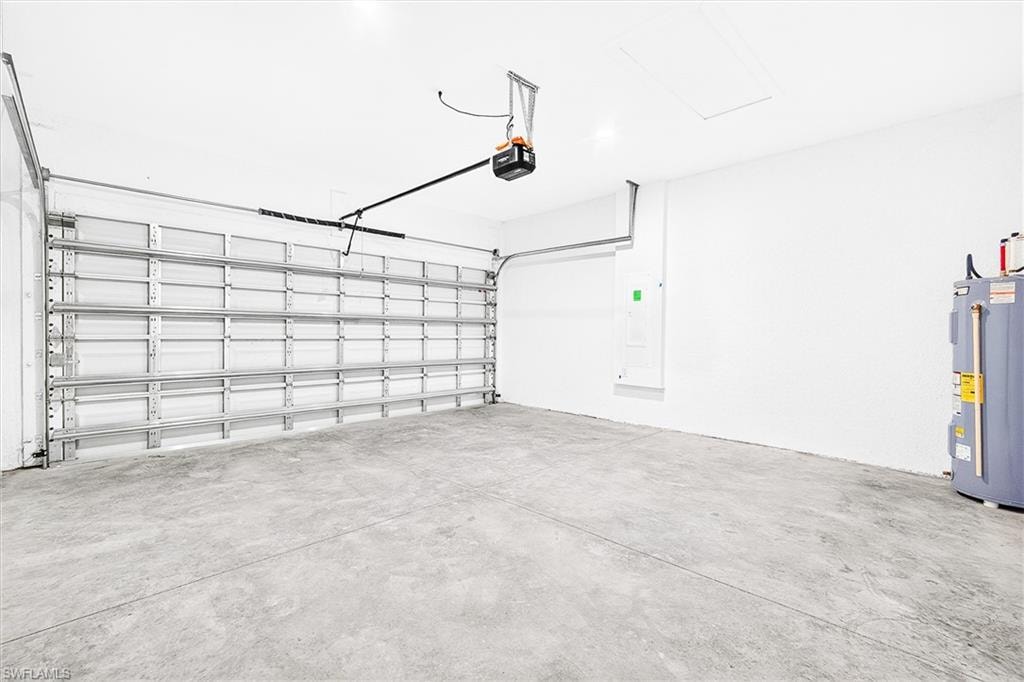 Attached garage featuring a concrete floor, automatic garage door opener, and a panel for electrical distribution