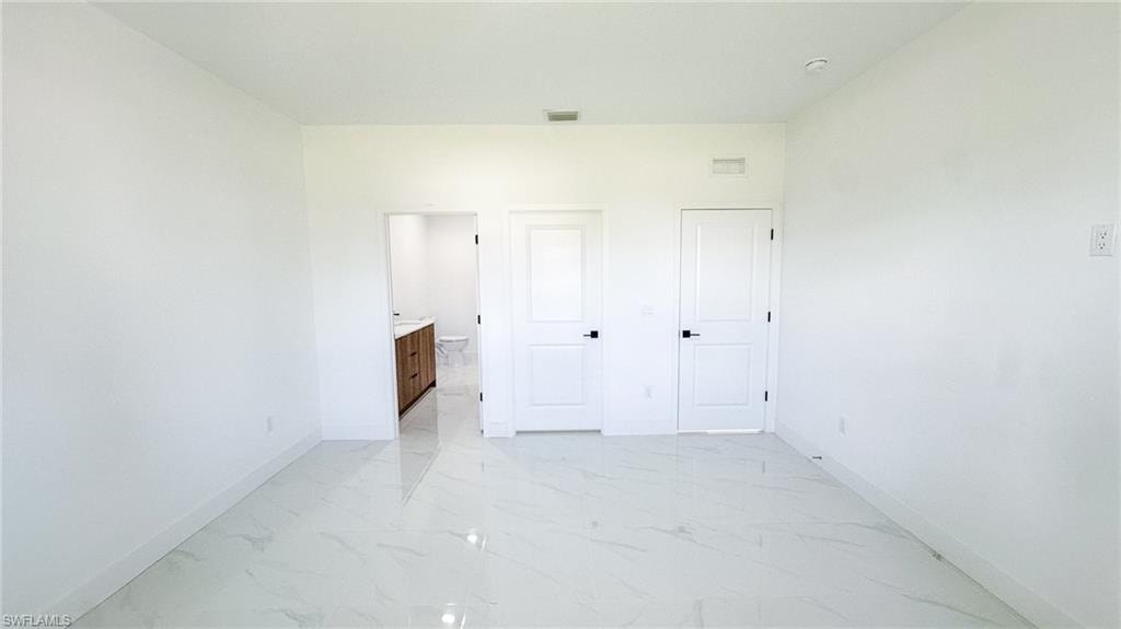 Bright, open room with pristine polished concrete flooring, white painted walls, and multiple white six-panel doors providing flexible entry and exit points