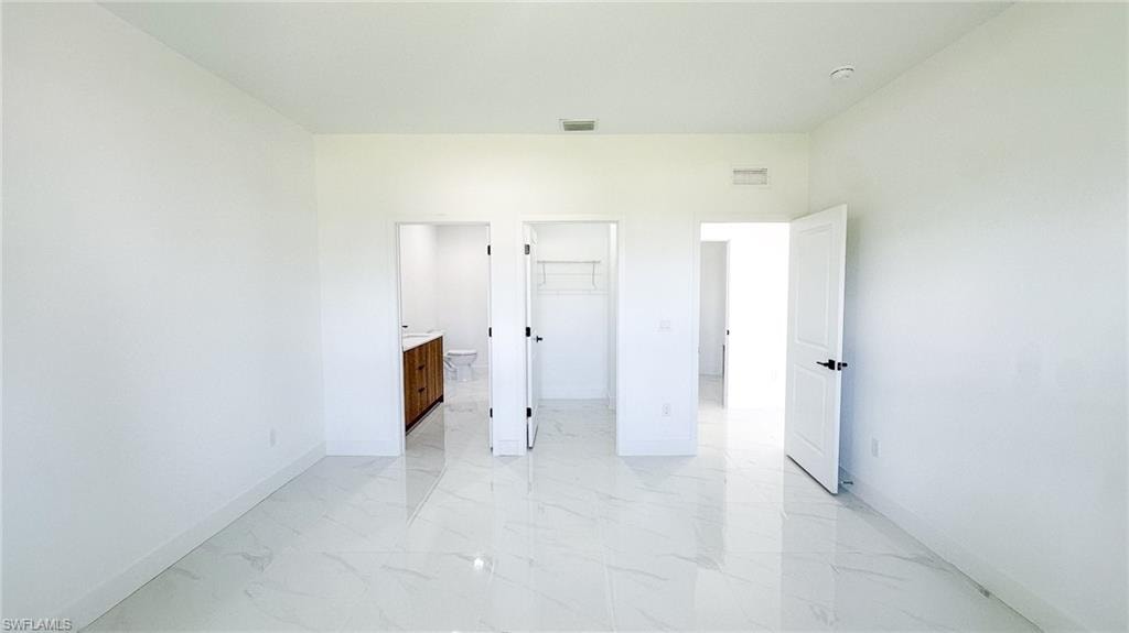 Bright, open interior featuring polished concrete flooring throughout, multiple white painted doors with modern hardware, and clean white walls with recessed ceiling lighting