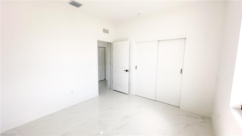 Spacious bedroom with pristine light-finish flooring, white painted walls, and abundant natural light from multiple windows