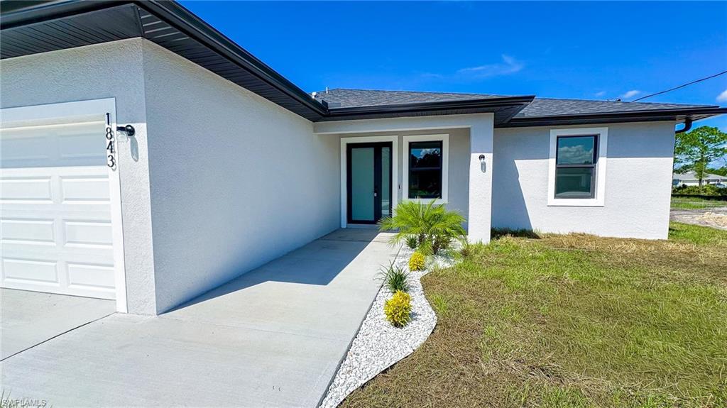 Stucco exterior with black trim accents and a white garage door
