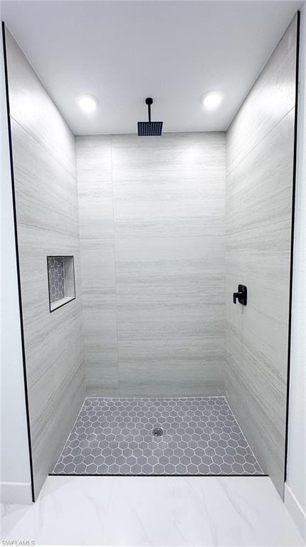 Enclosed shower with large format wall tiling, hexagonal floor tiling, a built-in shower niche, and matte black fixtures