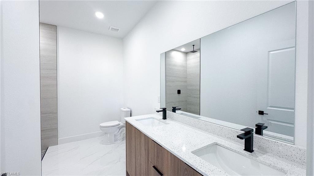Dual vanity with speckled white countertop, wood-finish cabinetry, and matte black fixtures