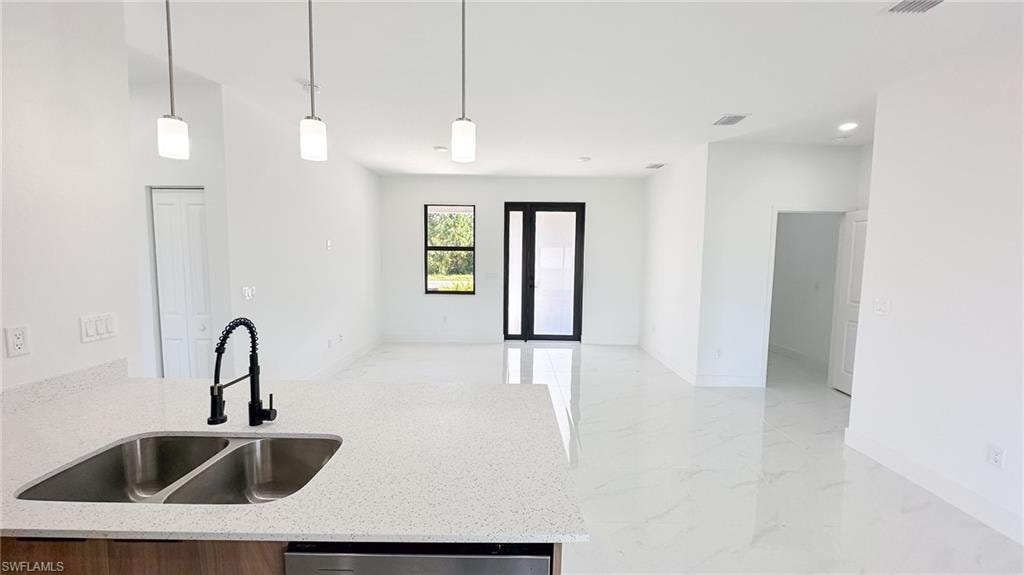 Open-concept kitchen and living area featuring a white quartz countertop with dual stainless steel sink, matte black gooseneck faucet, white cabinetry, polished concrete flooring, and recessed ceiling lighting