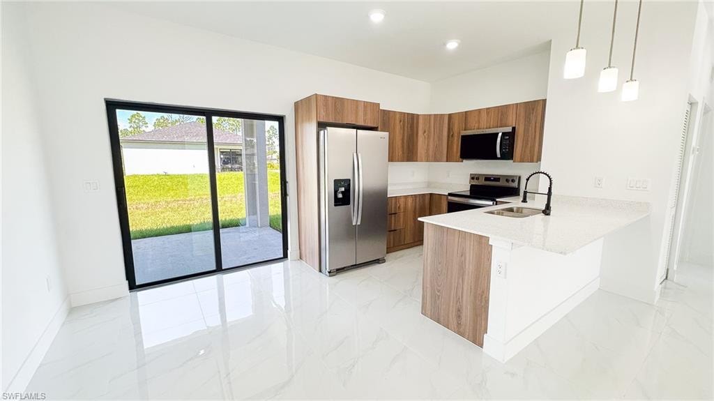 Modern kitchen featuring wood-finish cabinetry, stainless steel appliances, white quartz countertops, a large center island with waterfall edge, and polished white porcelain flooring