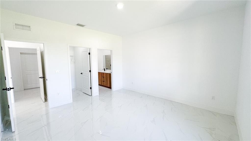 Bright, open interior space featuring pristine light-finish tile flooring throughout, recessed ceiling lighting, and multiple white interior doors with dark hardware